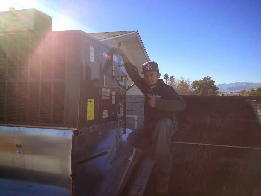 HVAC technician performing Boiler Repair on a rooftop unit in Opp
